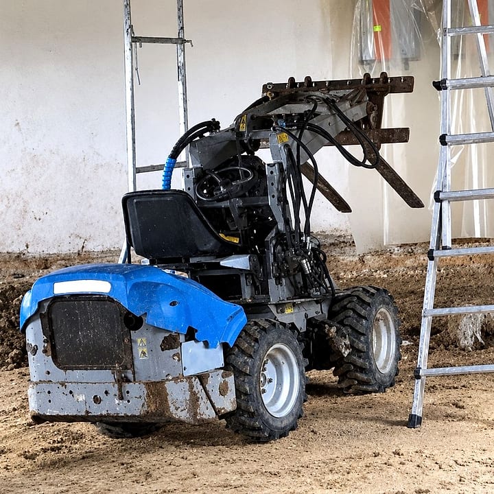 Blue mini loader with pallet forks on a building site